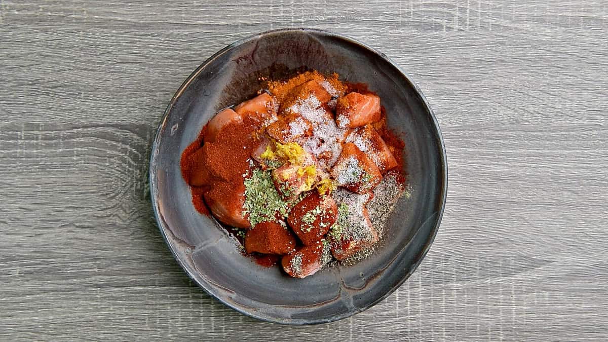 Pieces of salmon in a bowl with spices.