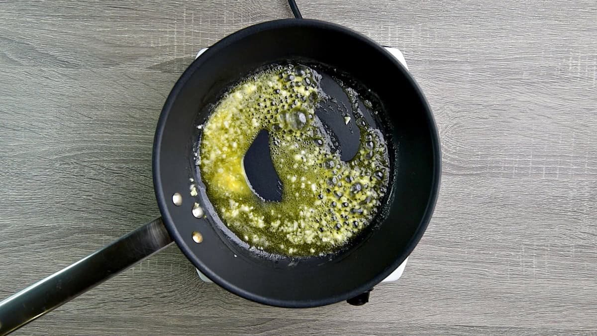 Butter and minced garlic cooking in a skillet.