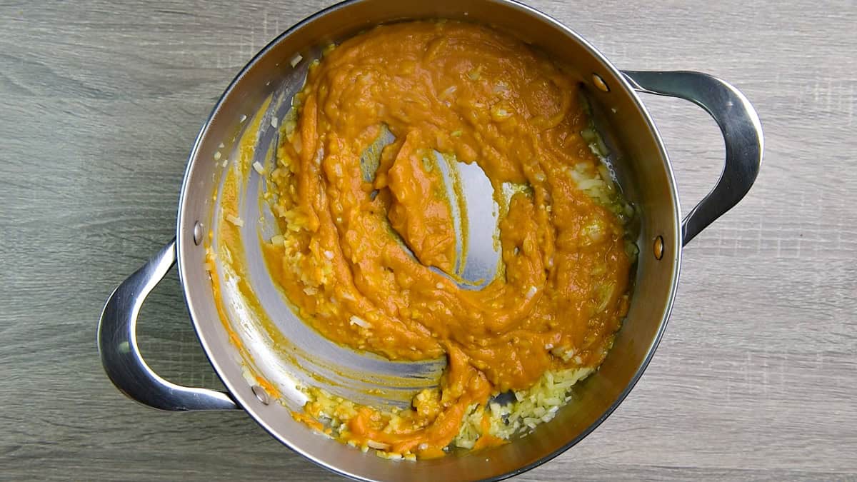 Pumpkin puree cooking in a pot with onion and garlic.