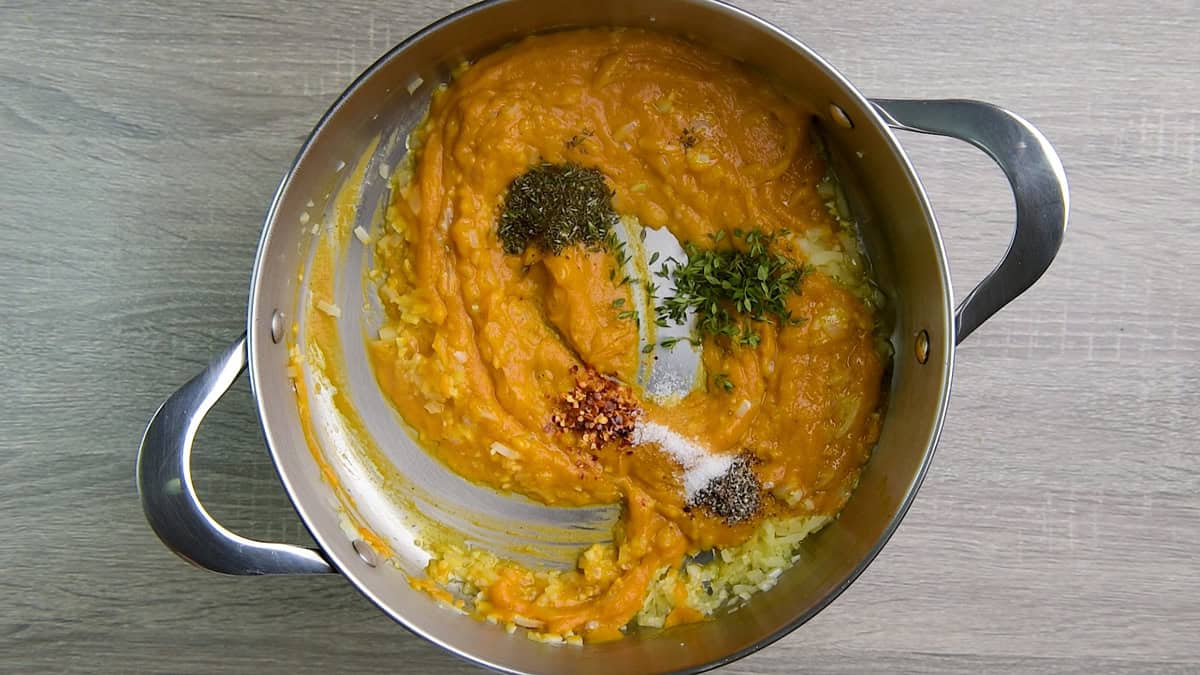 Herbs and seasonings added to the pumpkin puree in a pot.