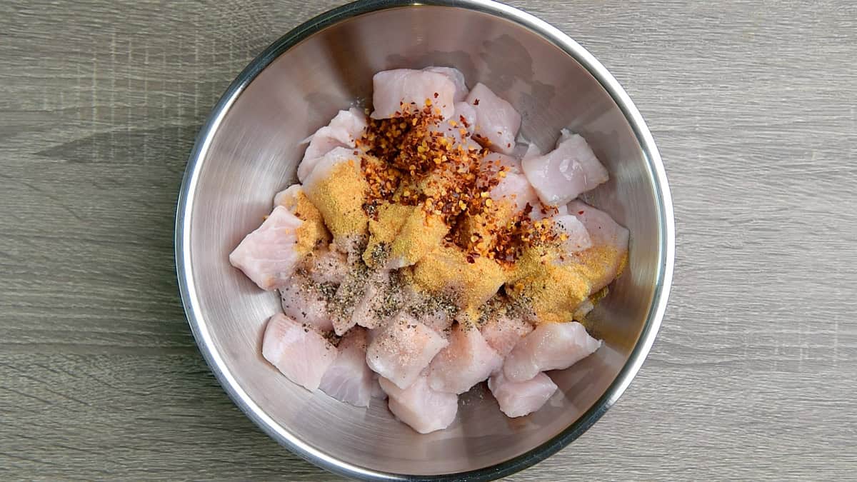 Add seasonings to cubed fish in a bowl.