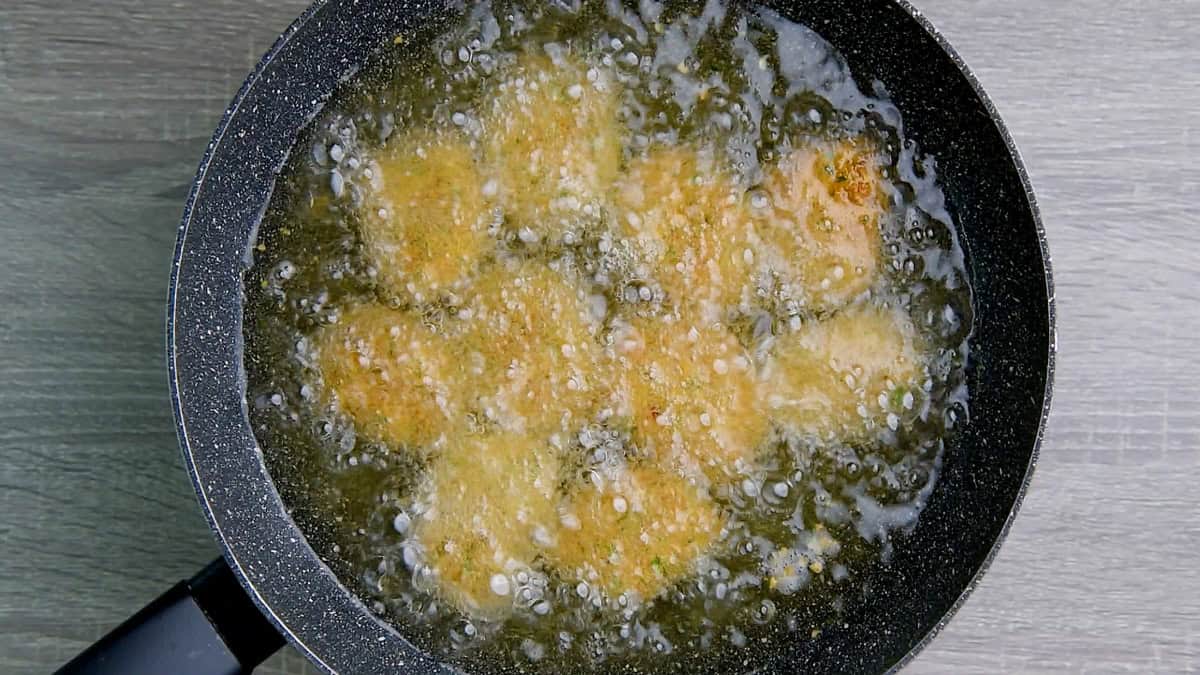 Fish nuggets being fried in a pan of oil.